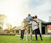 family hugging outside their new house